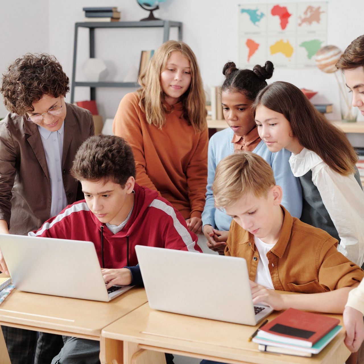 A group of children are looking at laptops in a classroom