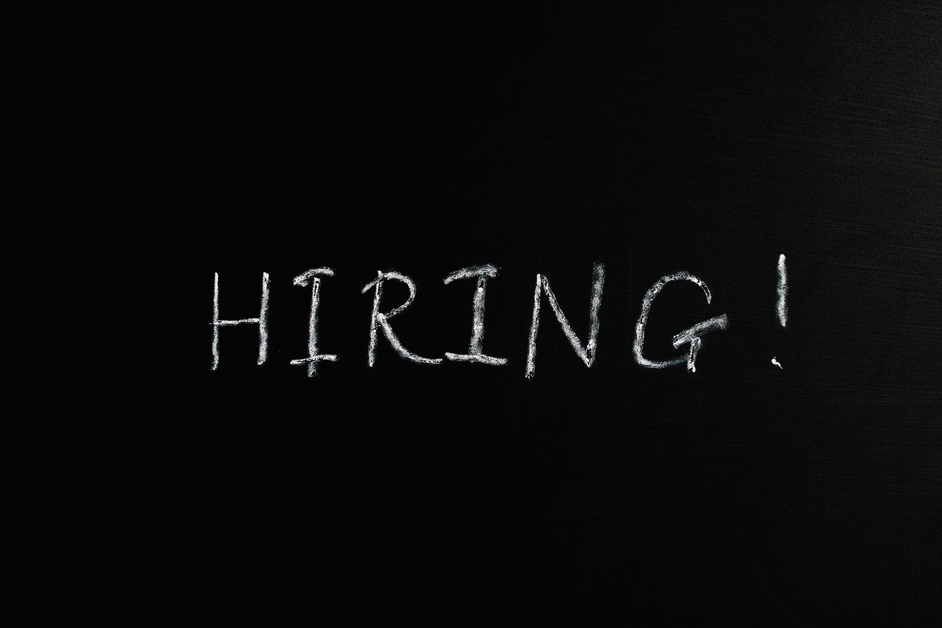 The word hiring is written in white chalk on a blackboard
