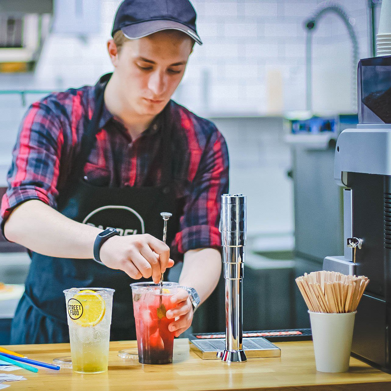 A man in an apron is preparing a drink with straws