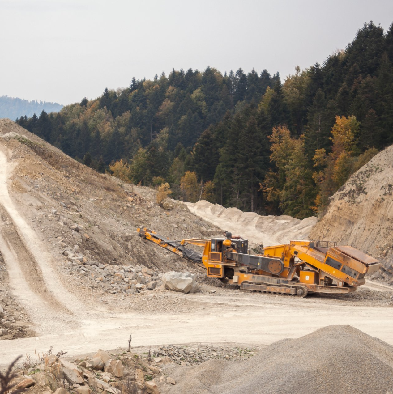 A large yellow truck is driving down a dirt road