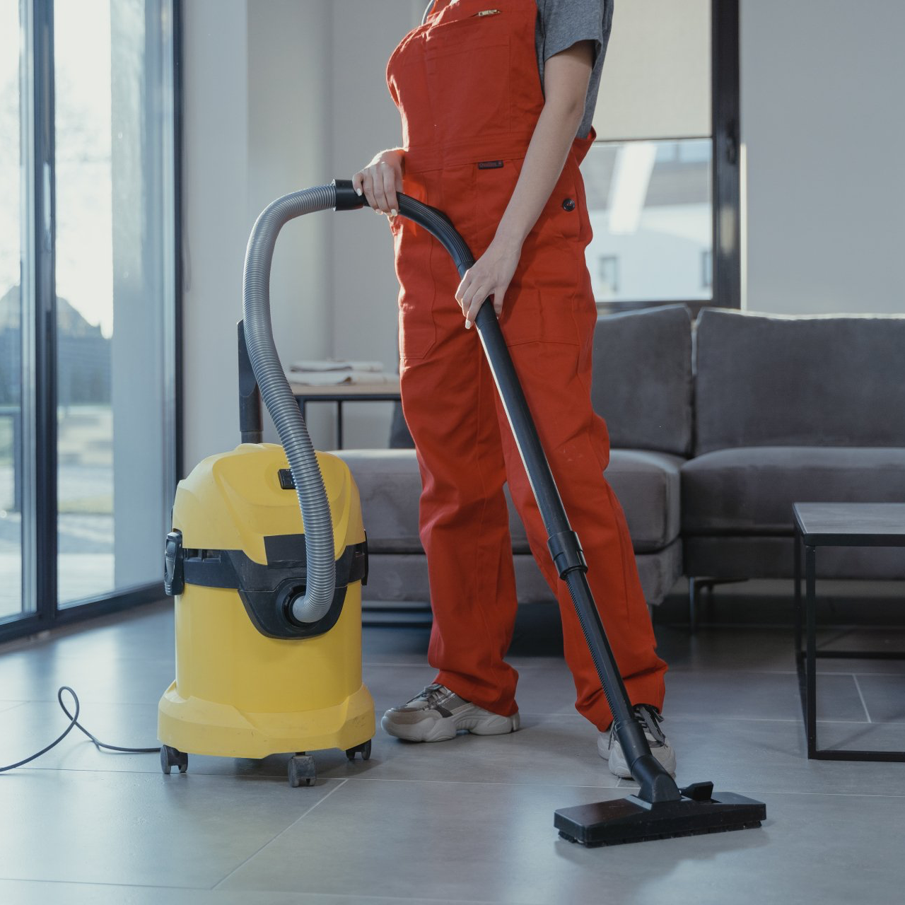 A woman is using a yellow vacuum cleaner in a living room