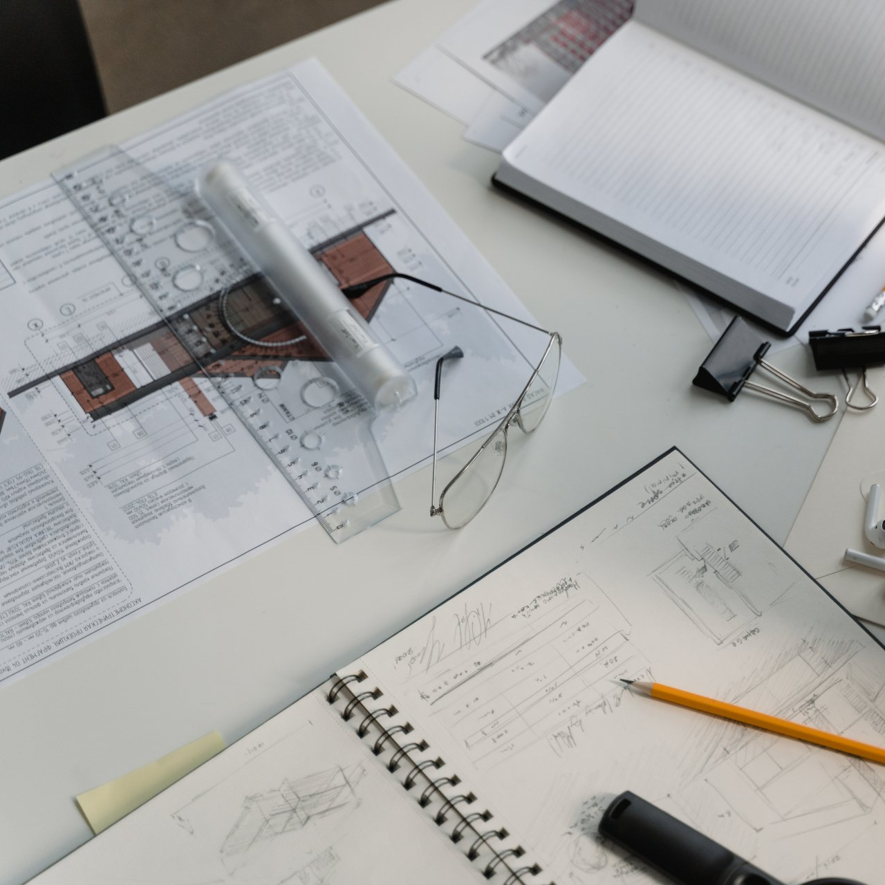 A desk with a notebook and a pair of glasses on it