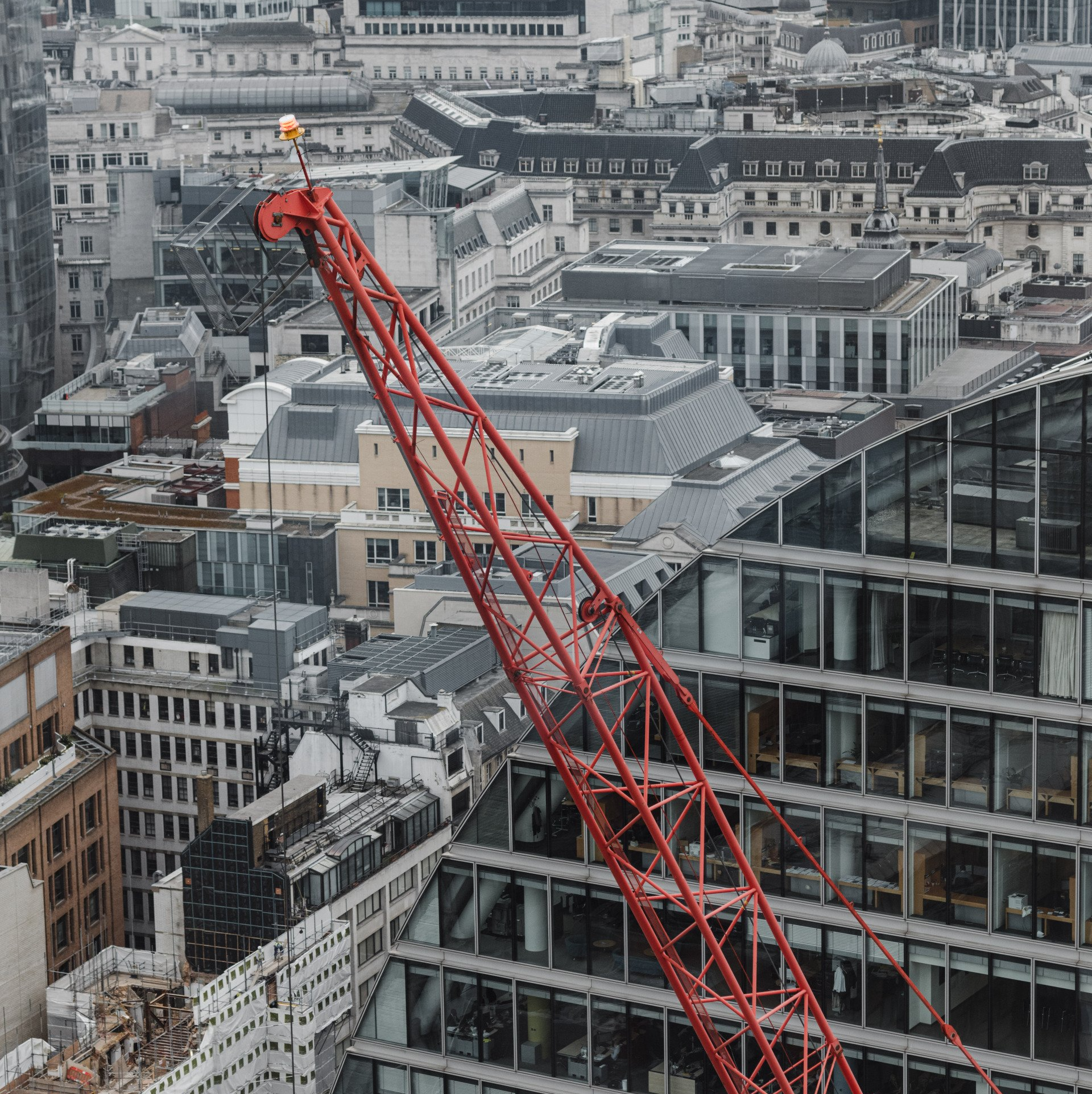 An aerial view of a city with a red crane in the foreground
