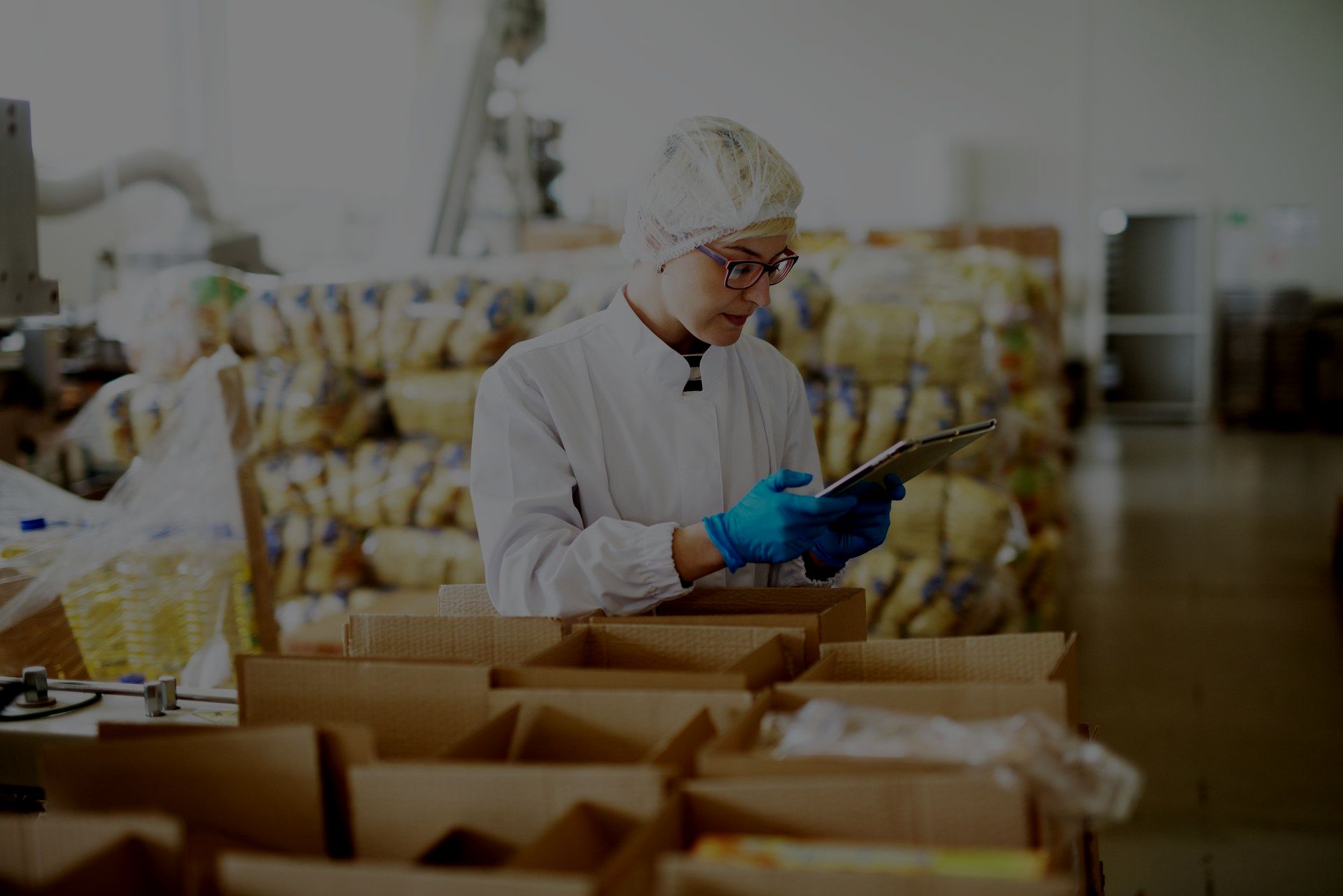 A man is looking at a tablet in a warehouse.