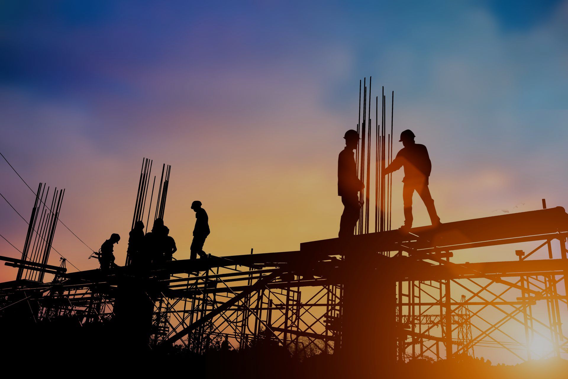 A group of construction workers are working on a construction site at sunset.
