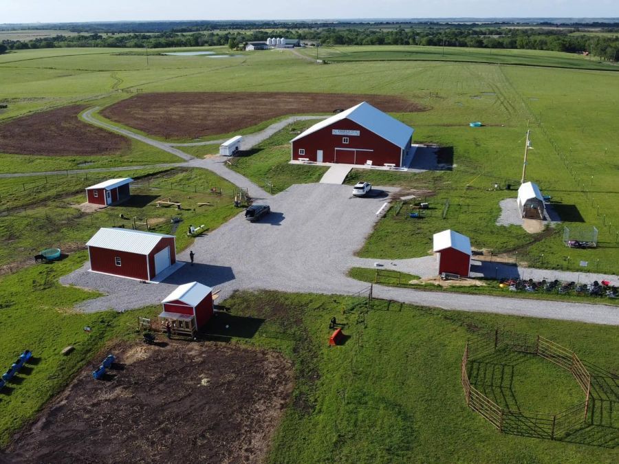 An aerial view of a farm with red barns and a baseball field.