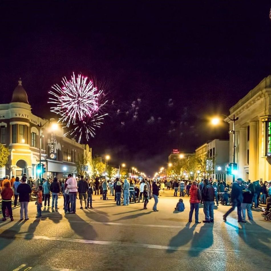 A crowd of people watching fireworks in a city at night