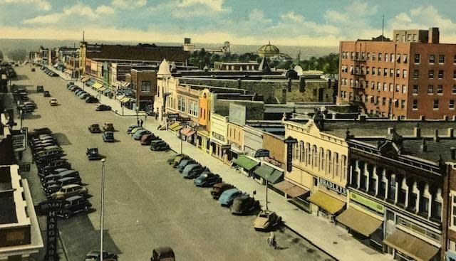 An aerial view of a city street with cars parked on the sidewalk