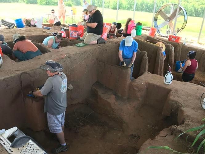A group of people are digging in a dirt pit.