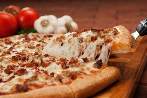A pizza with a slice taken out of it on a cutting board.