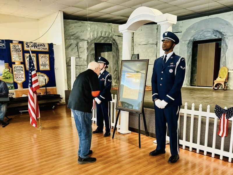 A man in a military uniform is talking to another man in a museum room.
