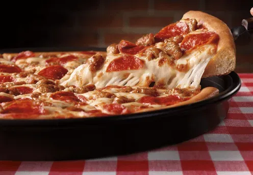 A person is taking a slice of pepperoni pizza from a pan.