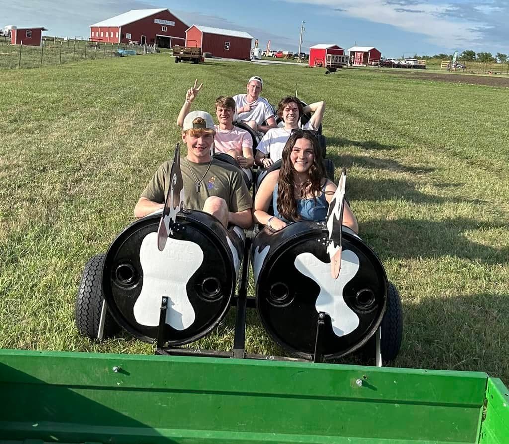 A group of people are riding a tractor in a field.