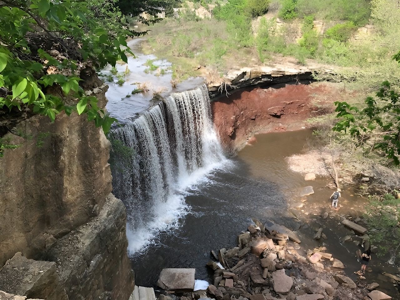 A waterfall is surrounded by rocks and trees in the middle of a forest.
