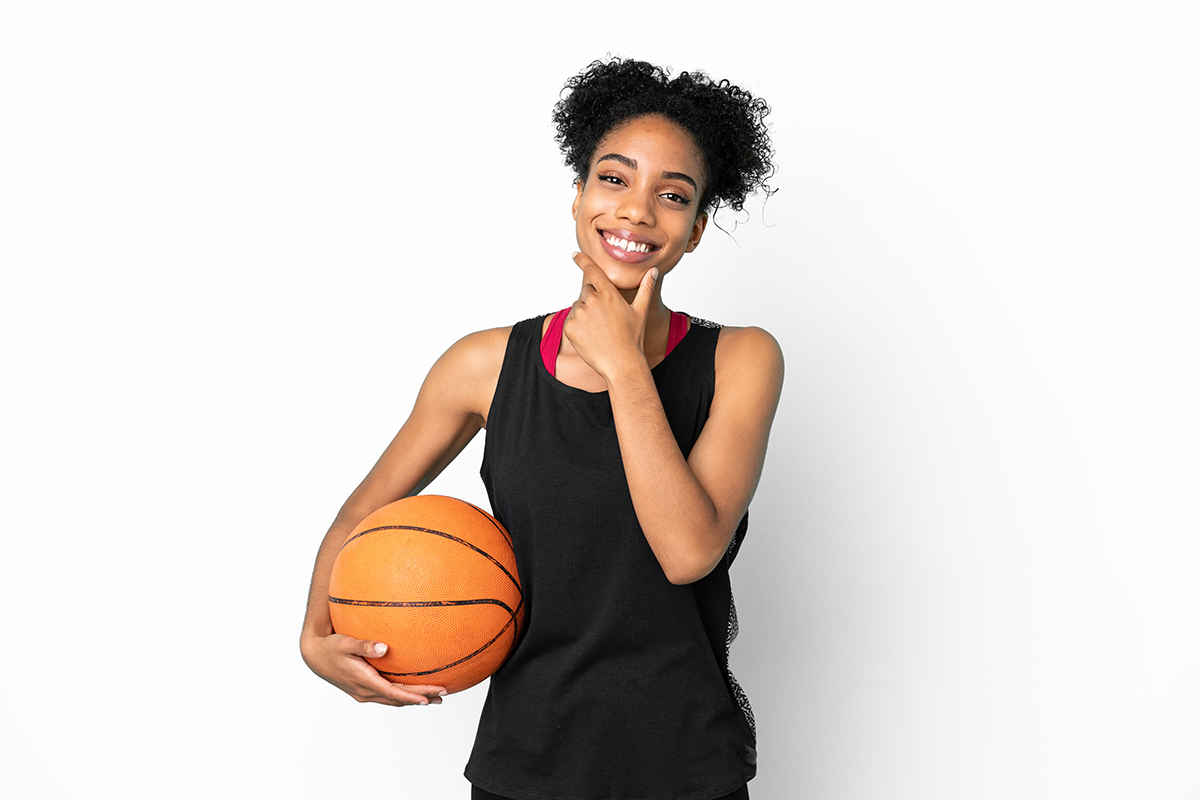Smiling person in a black tank top holding an orange basketball against a white background