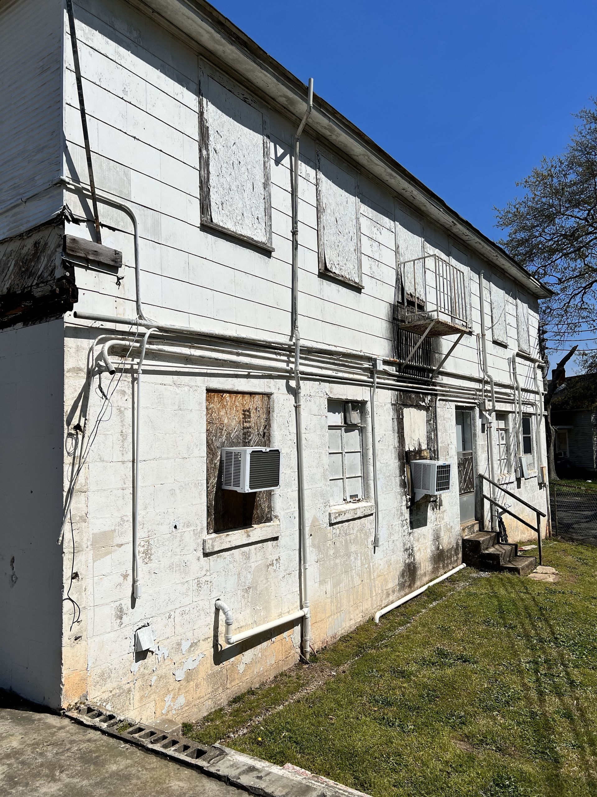 A white building with a lot of windows and air conditioners on the side.