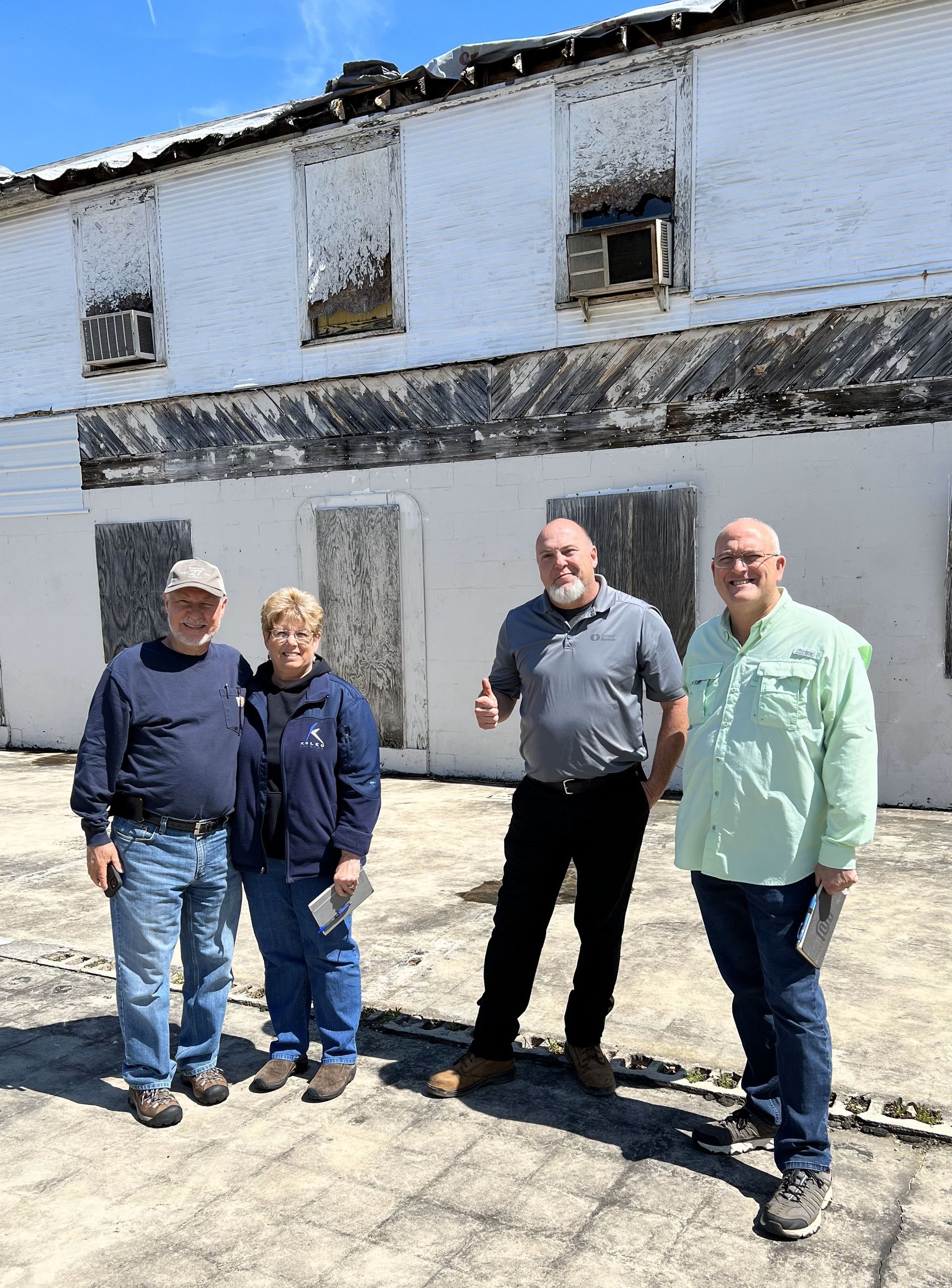A group of people are standing in front of a white building.