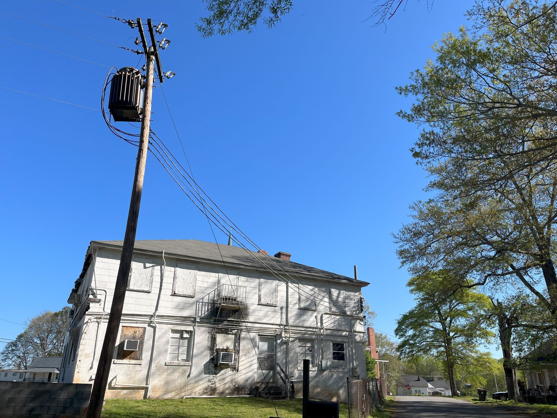 A telephone pole with a transformer on top of it in front of a house.