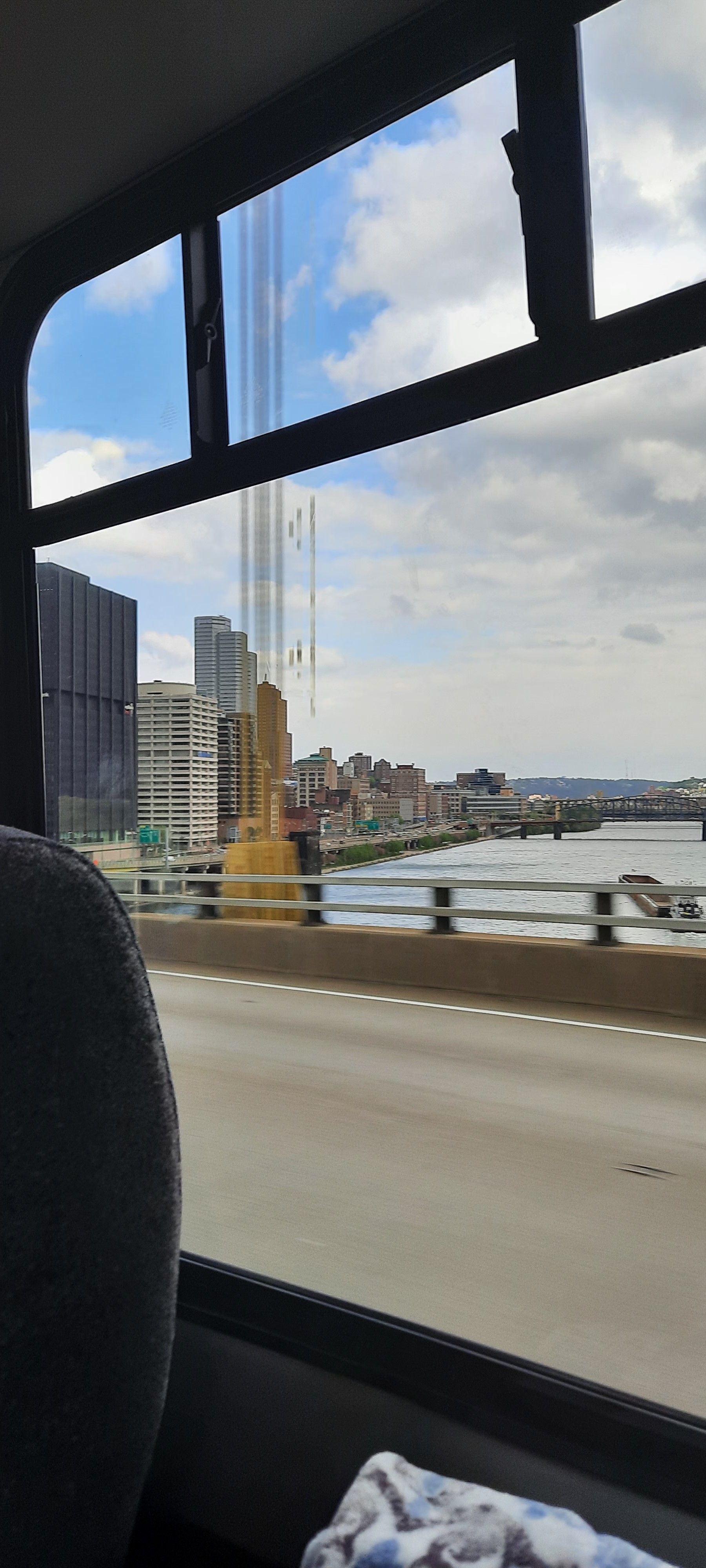A person is sitting in a car looking out the window at a bridge.