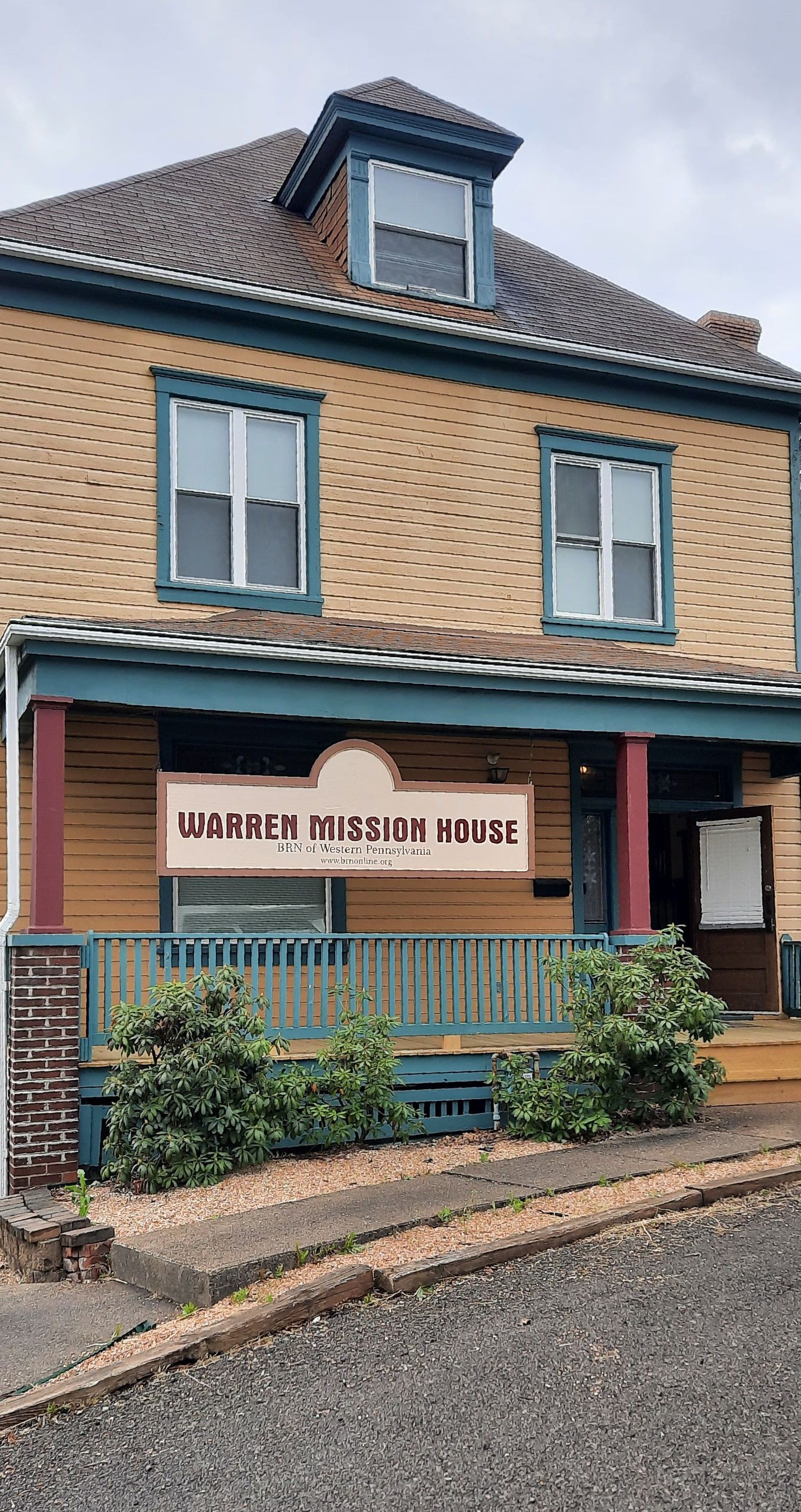 A large wooden house with a sign on the front porch.