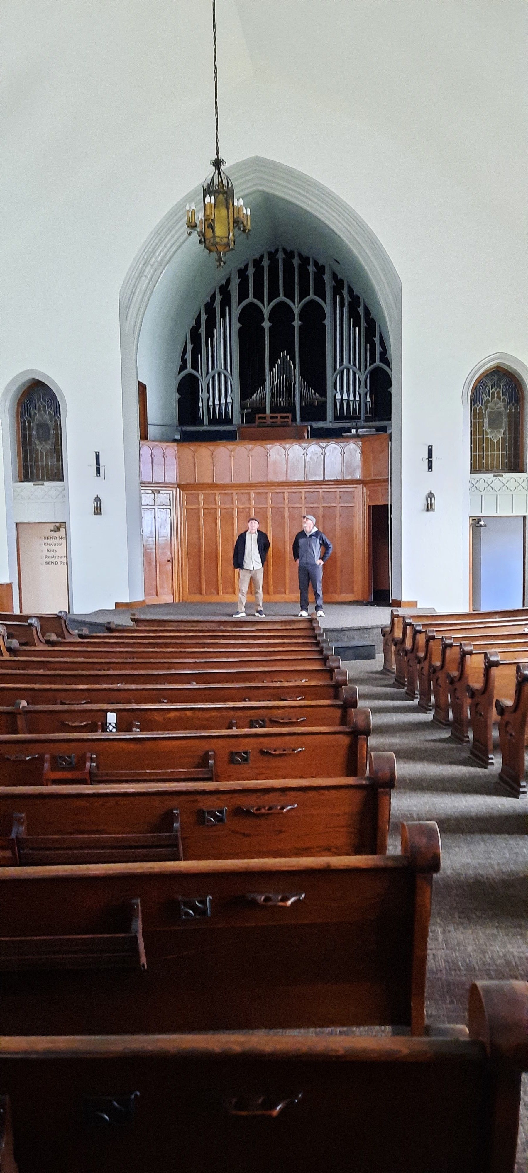 Two men are standing in the aisle of a church.