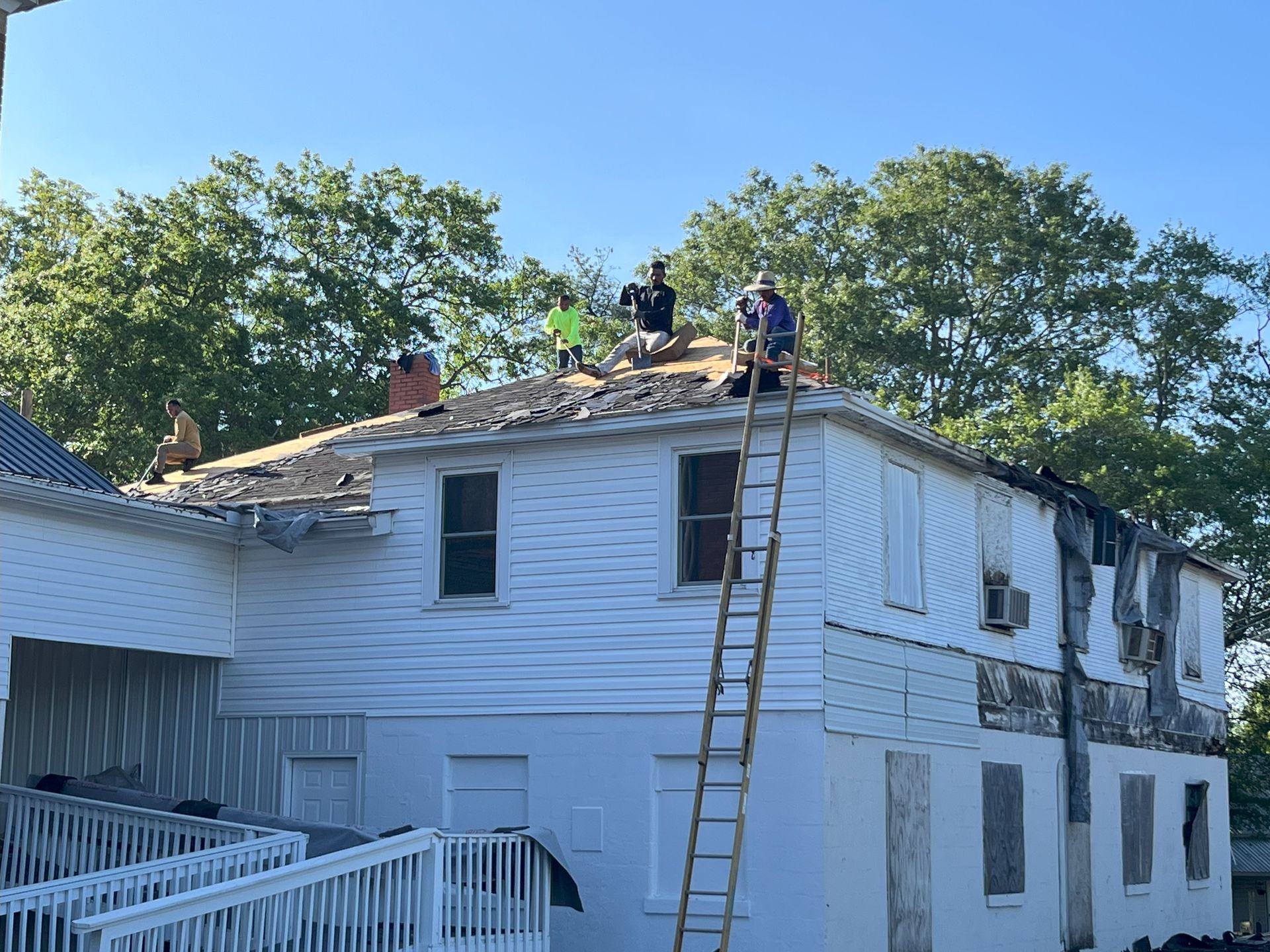 A group of people are working on the roof of a white house.