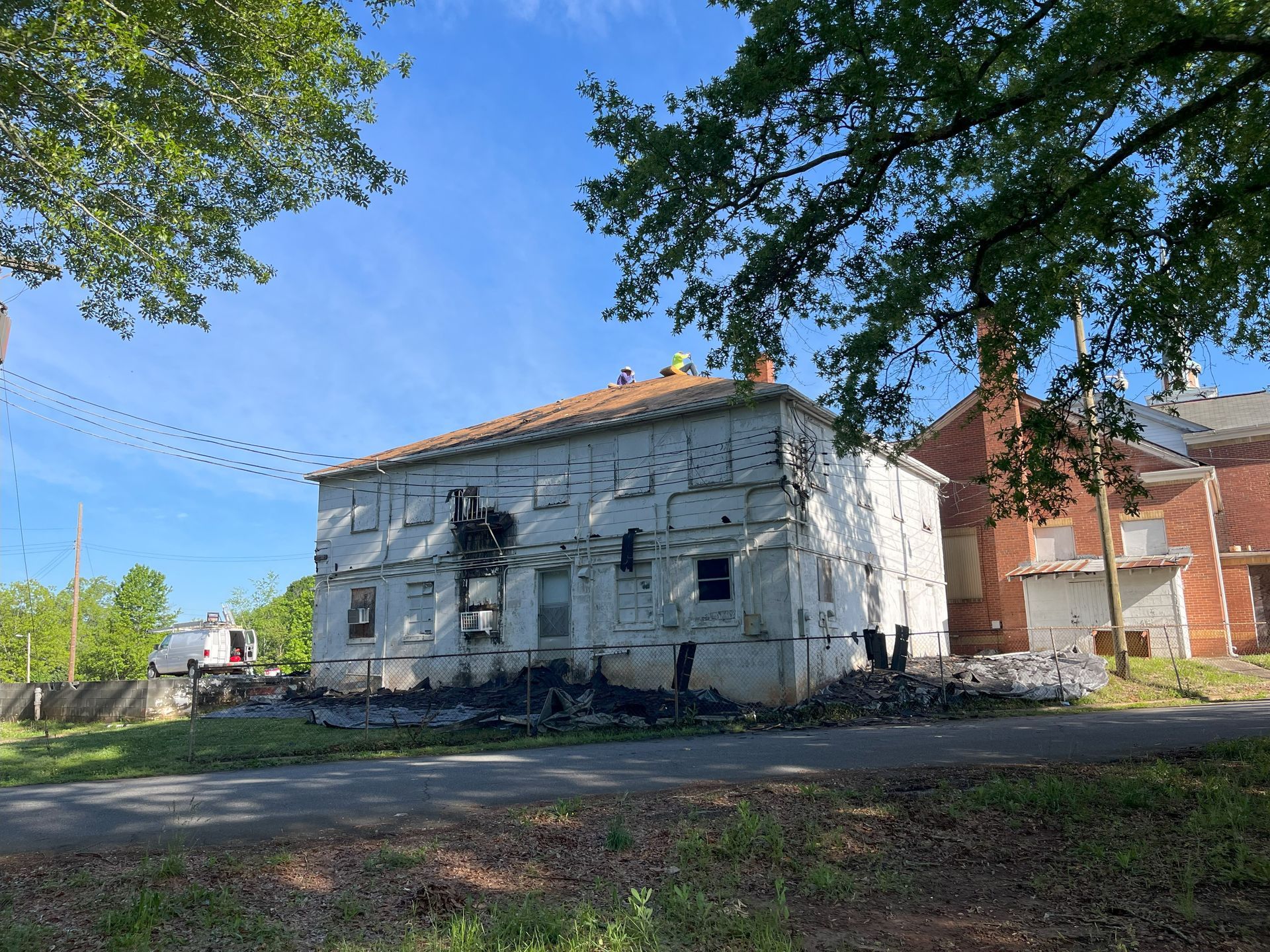 A large white building is sitting on the side of a road next to a tree.