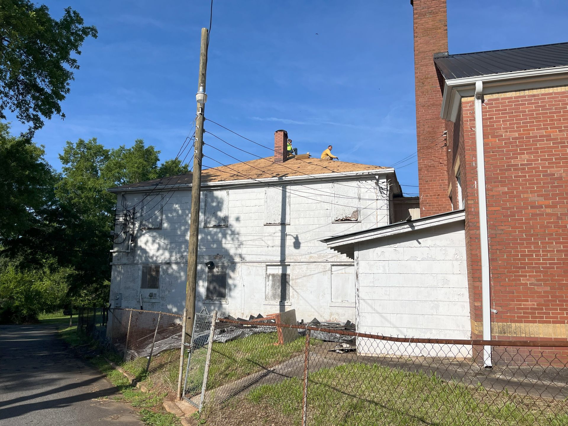 A brick building with a chimney on the roof is next to a white building.
