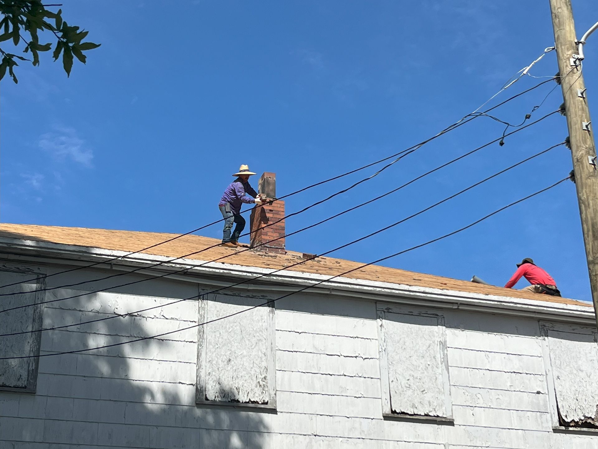 Two men are working on a chimney on the roof of a house