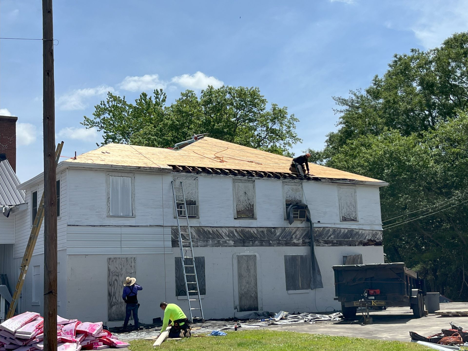 A group of people are working on the roof of a white house.