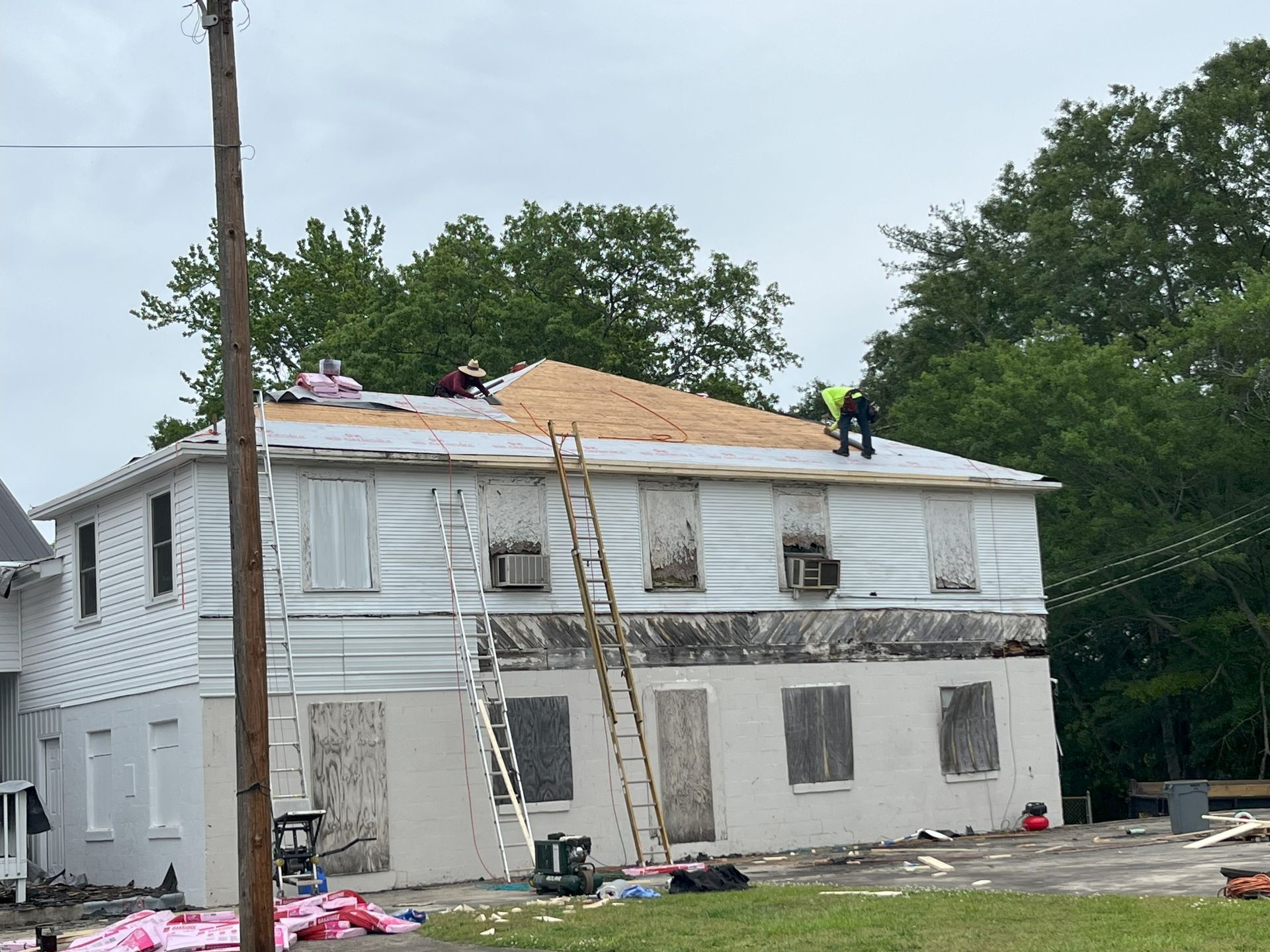 Two men are working on the roof of a white house.