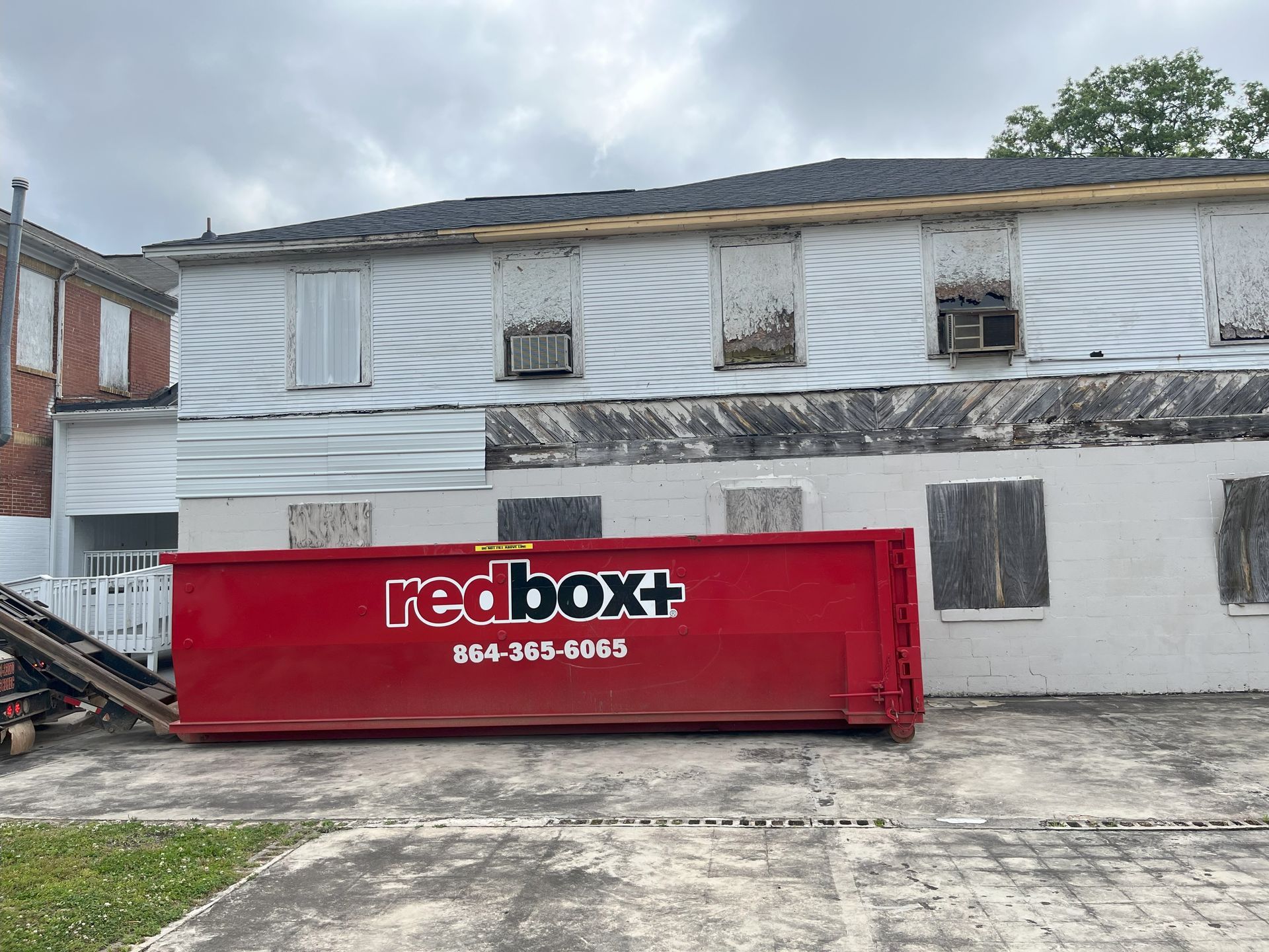 A red dumpster is parked in front of a white building.