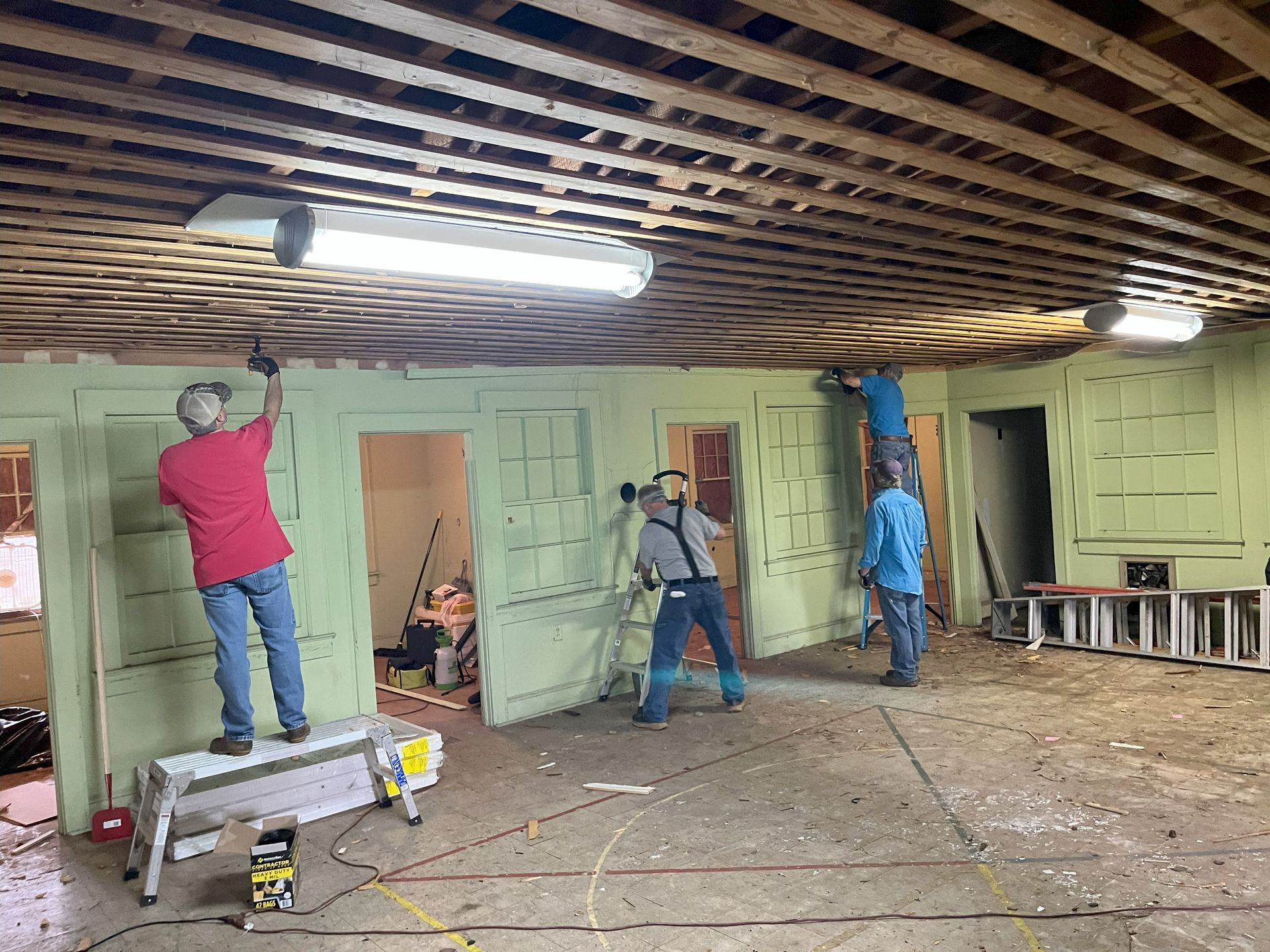 A group of people are working on the ceiling of a building.