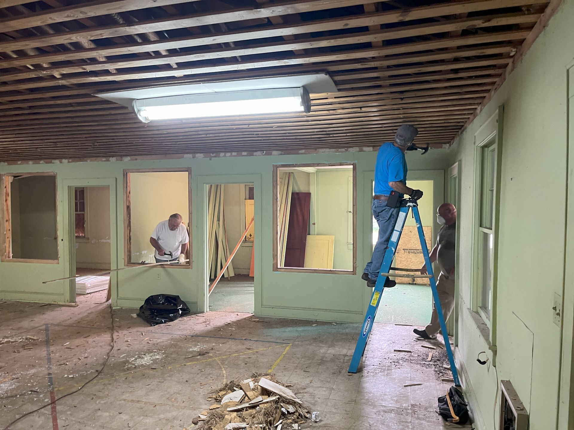 A man is standing on a ladder in an empty room.