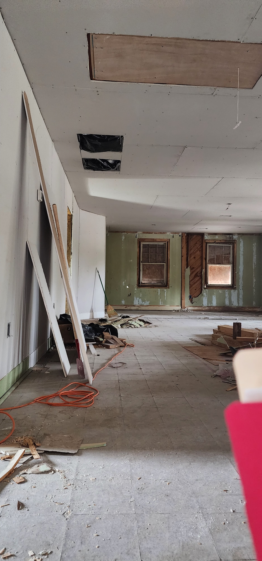 An empty room with a ladder and a red chair in it.