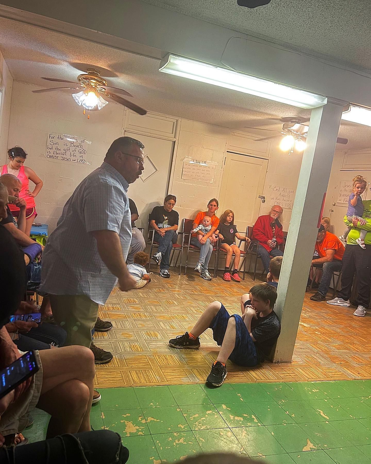 A man is standing in front of a group of people in a room.
