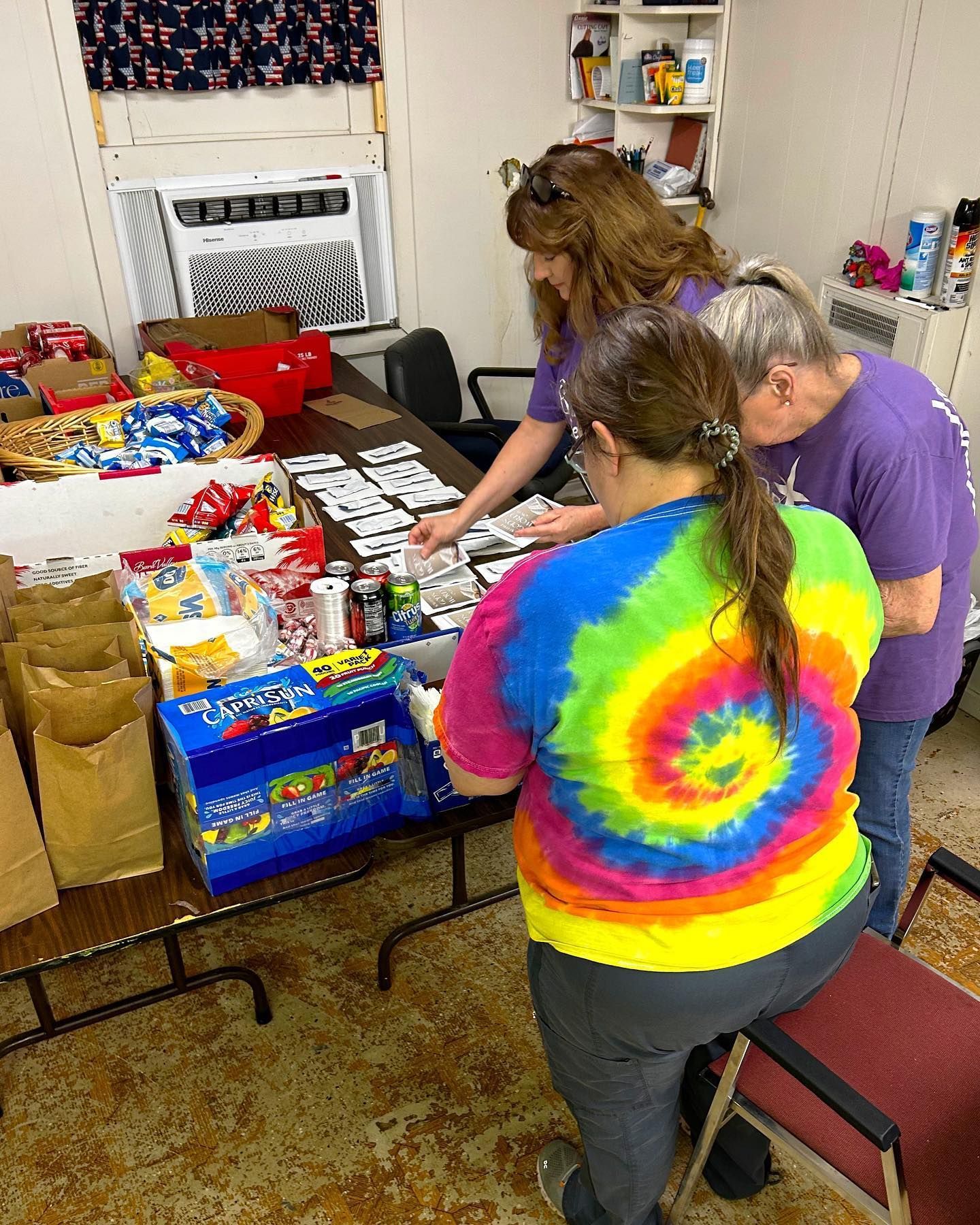 A group of women are standing around a table in a room.