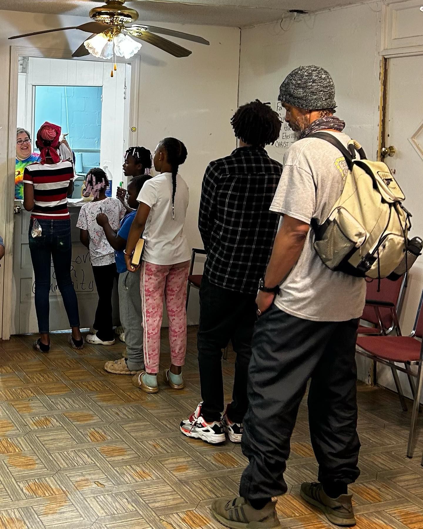 A group of people are standing in a room with a ceiling fan.