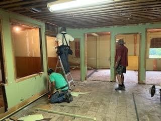 A group of men are working on a room in a house.