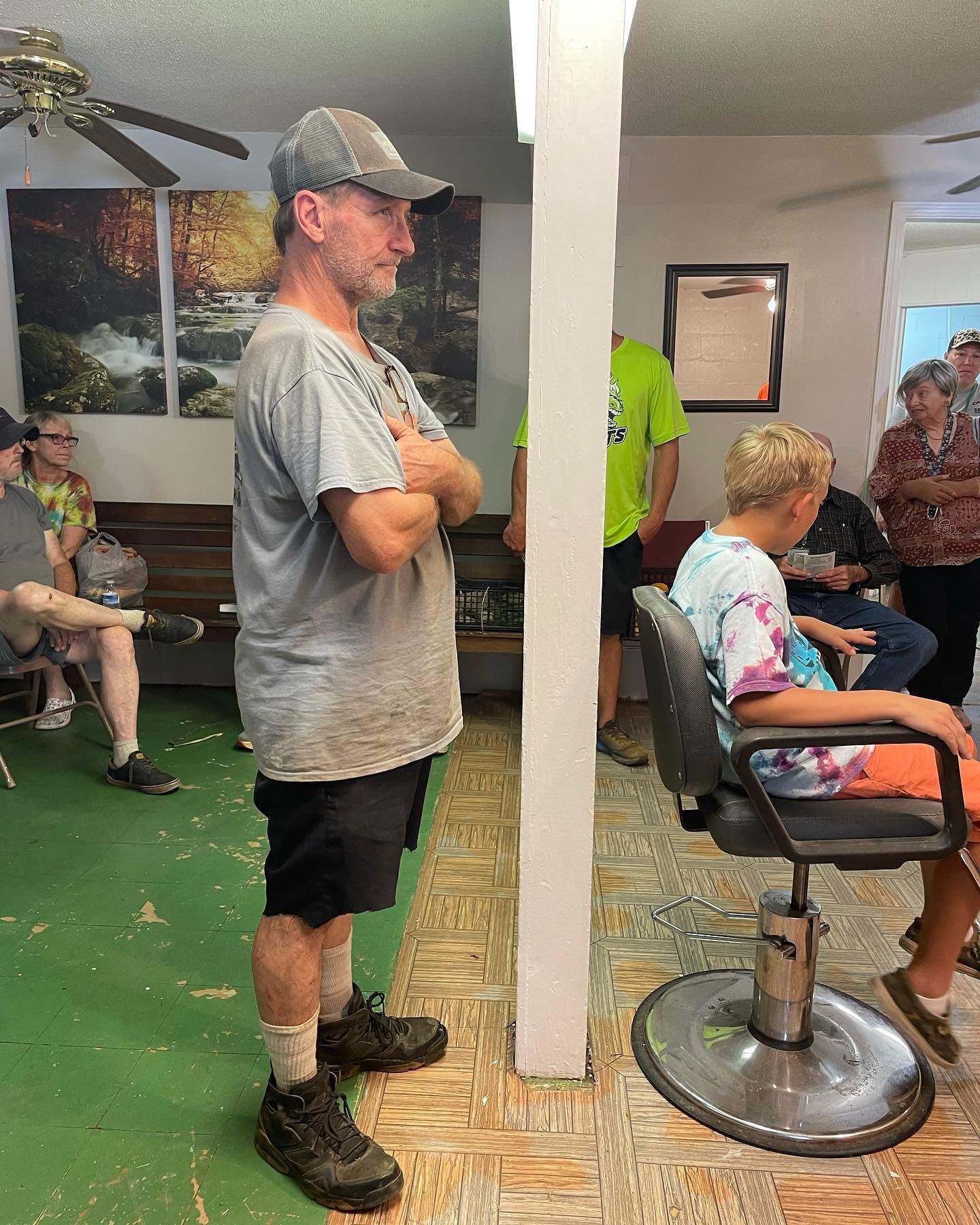 A man is standing in a room next to a boy sitting in a chair.