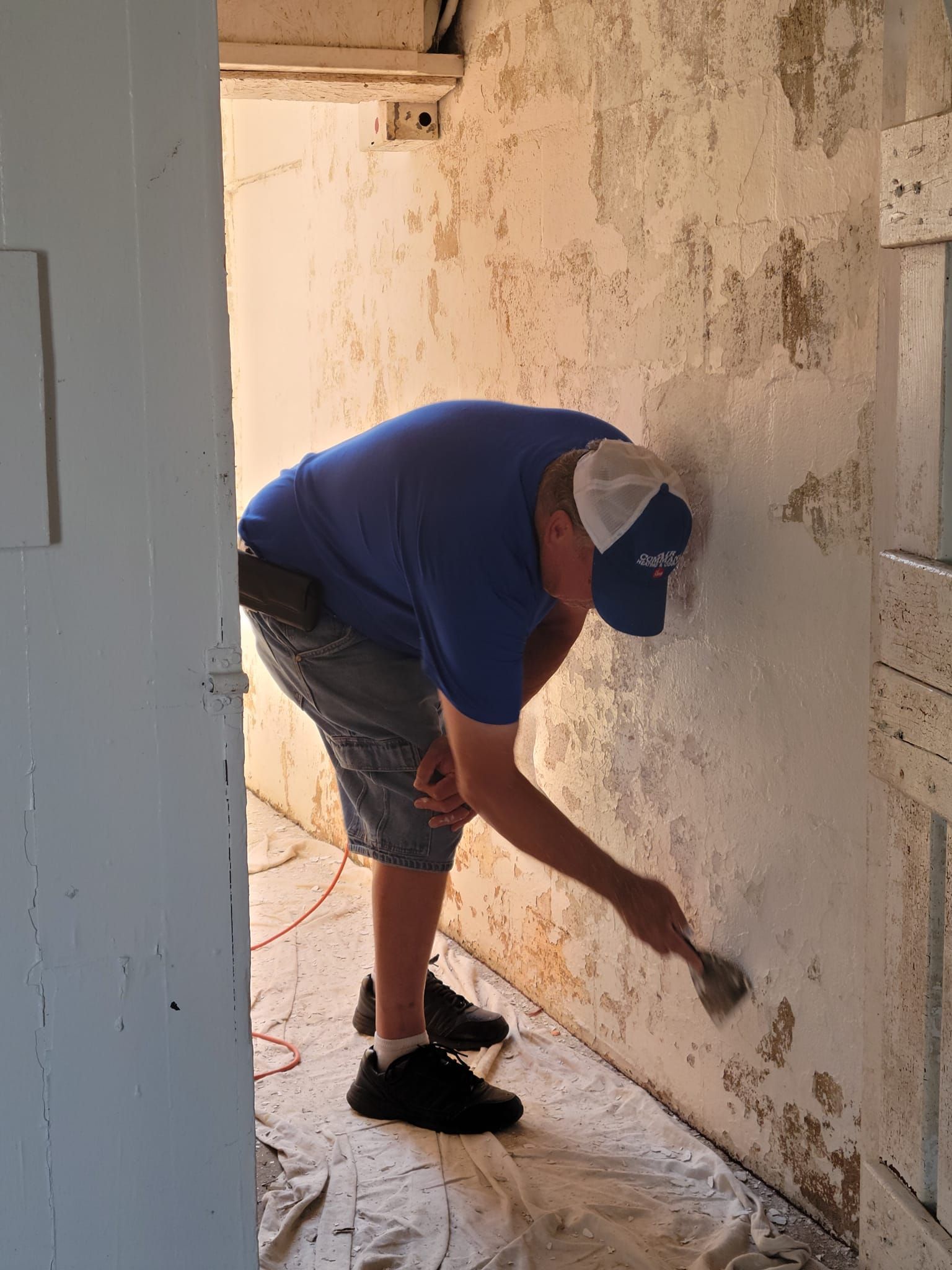 A man is painting a wall with a spatula.