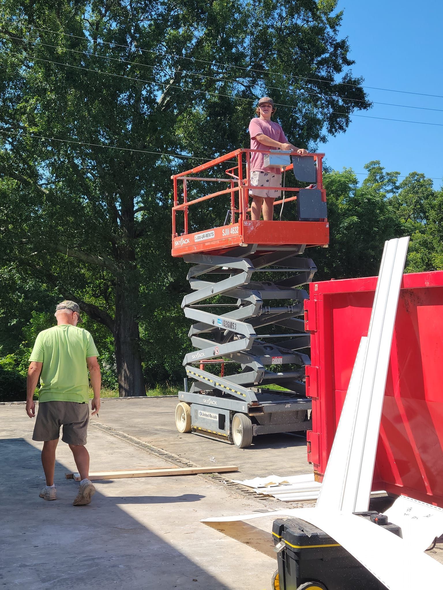 A man and a woman are standing on a scissor lift.