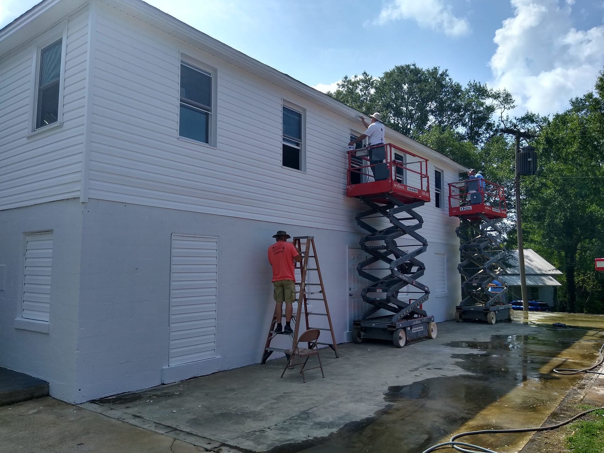 A group of people are painting the side of a house.