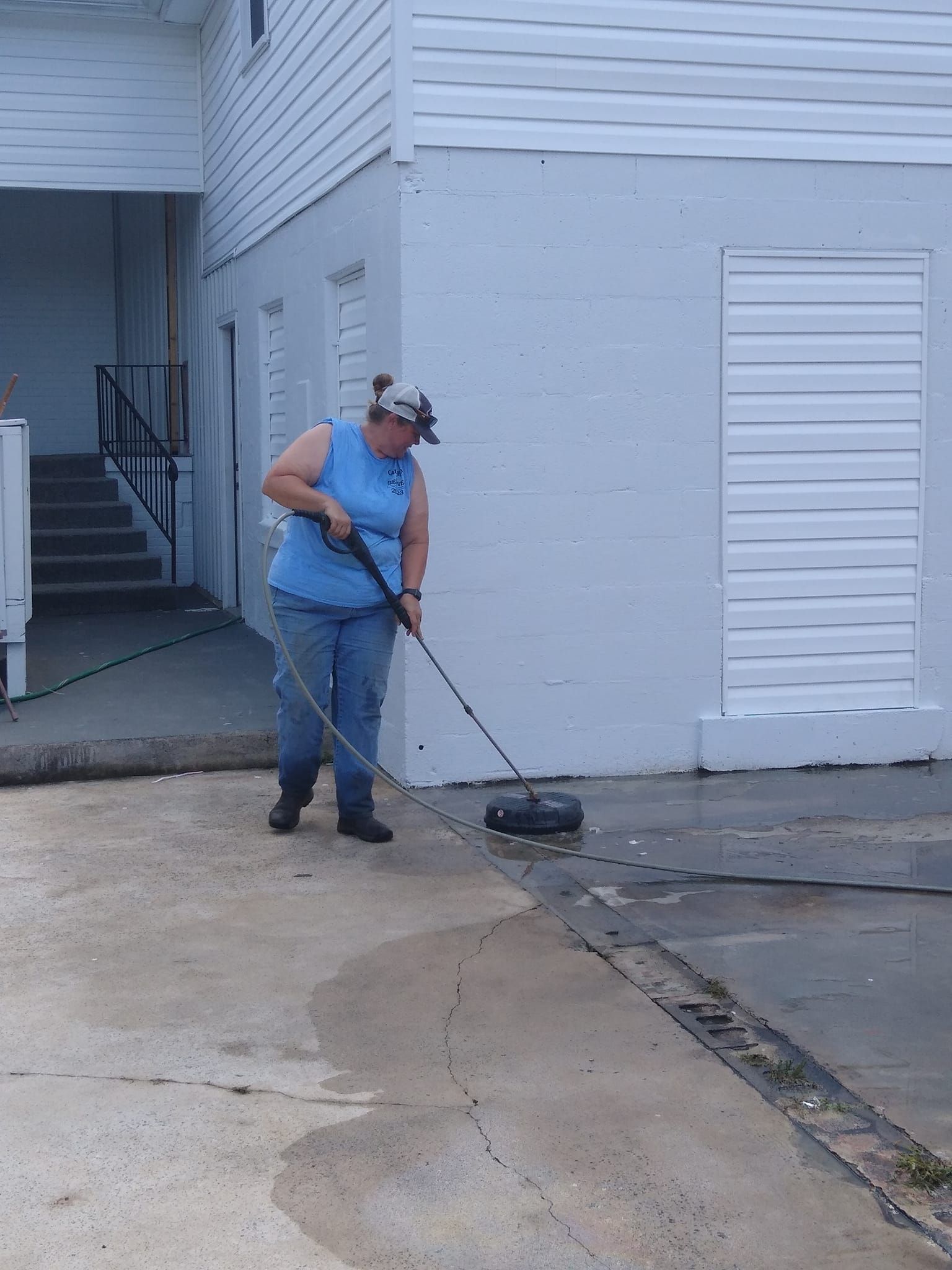 A woman is cleaning a driveway with a broom