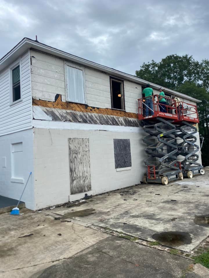 A group of people are working on a house with scissor lifts.