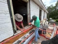 A group of men are working on a window on a house.