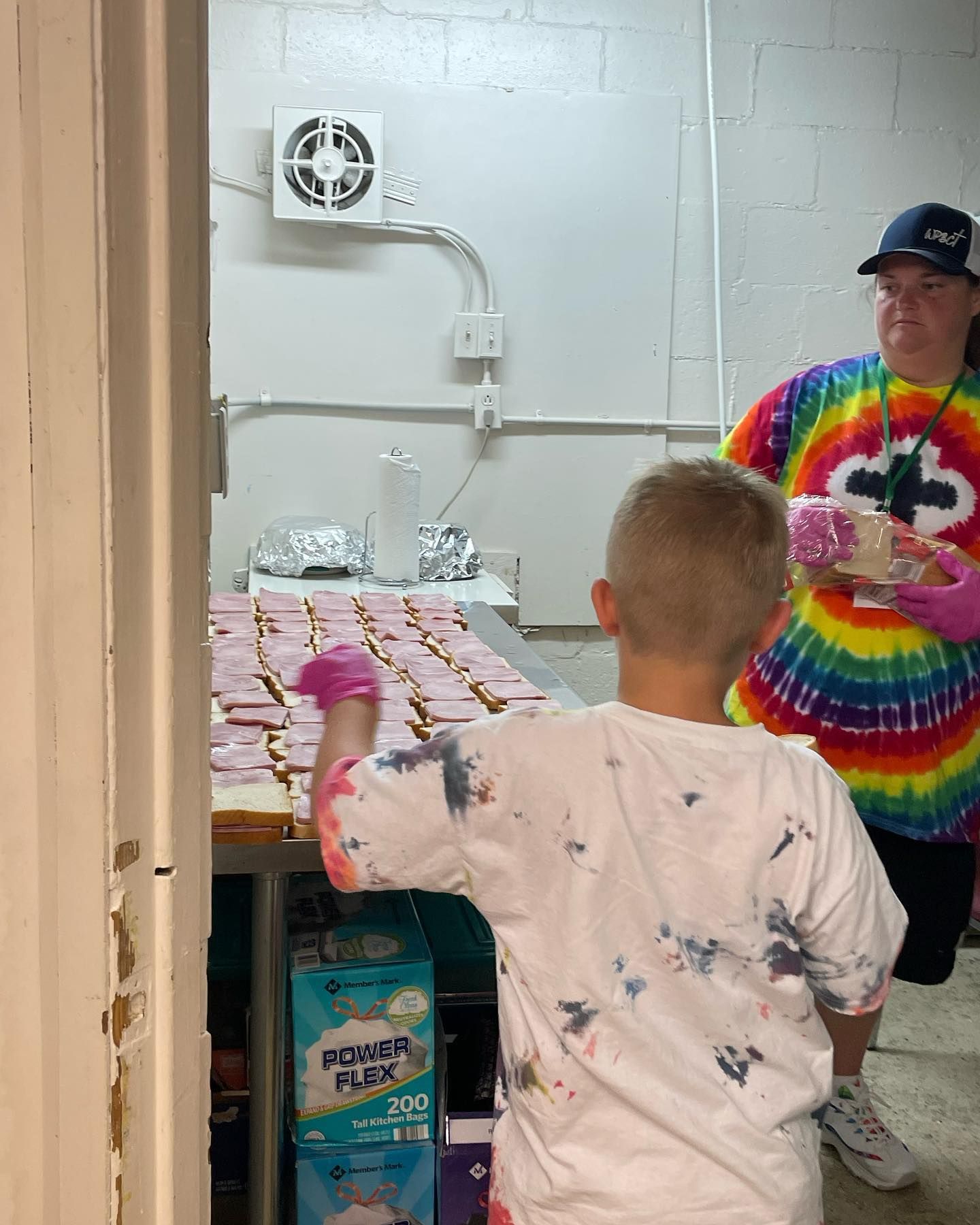 A boy is standing in front of a table with boxes of power flex diapers.
