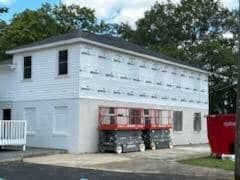 A white house with a gray roof is being remodeled.