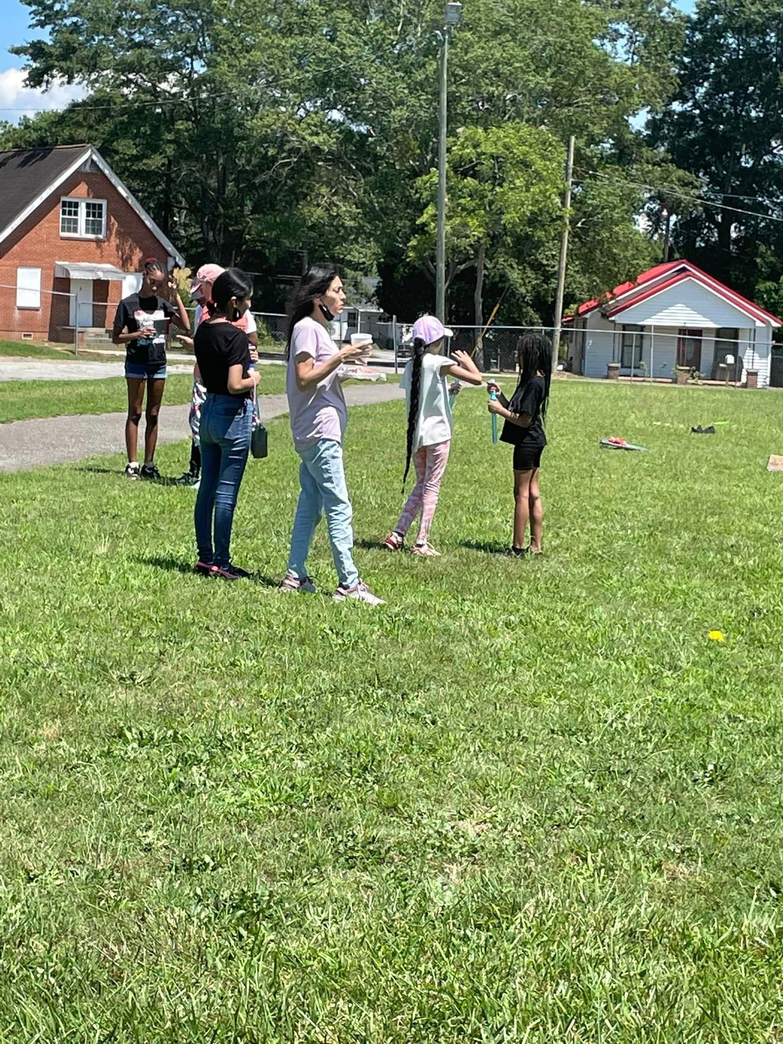 A group of people are standing in a grassy field.