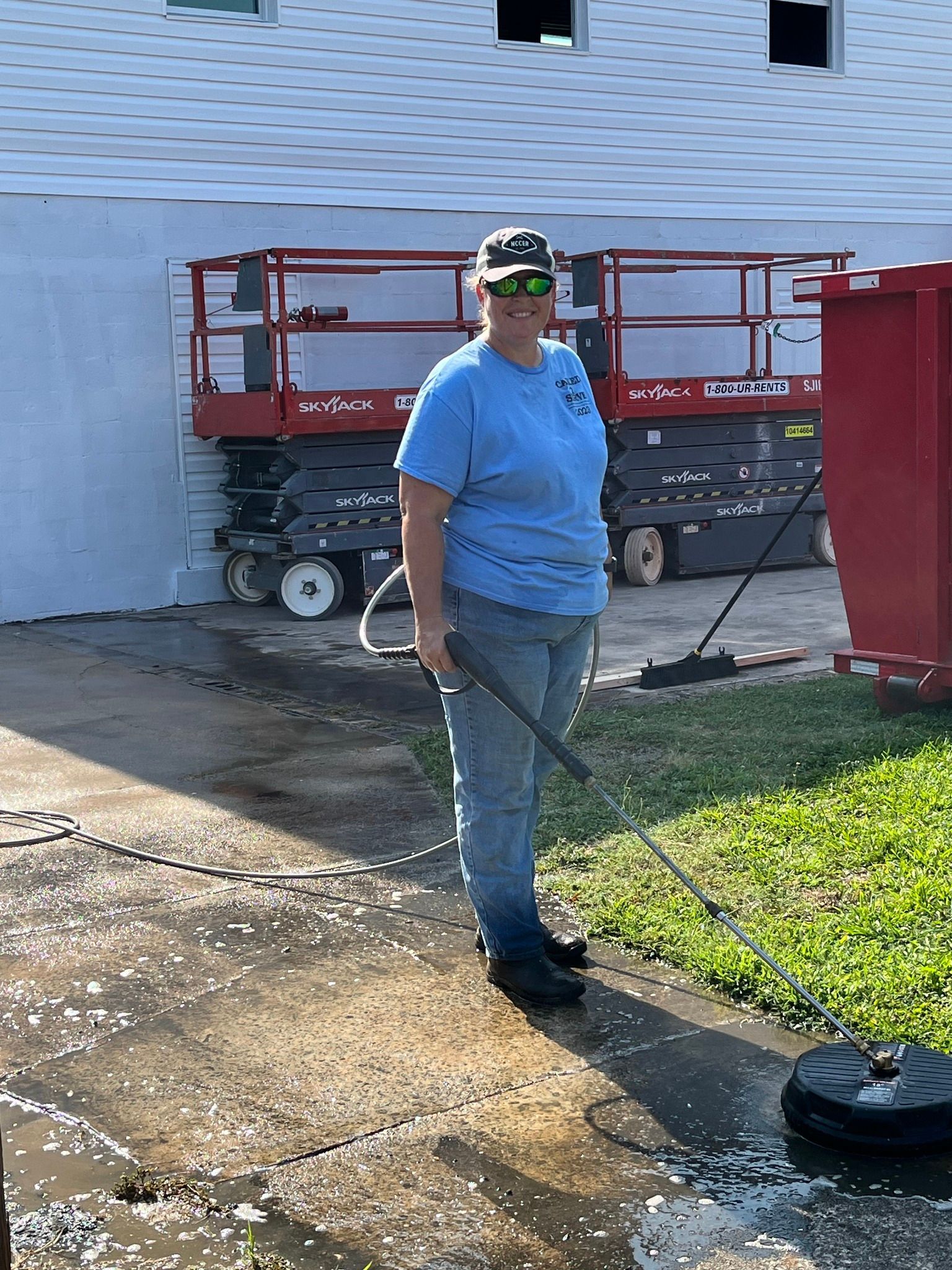 A woman is standing on a sidewalk holding a vacuum cleaner.